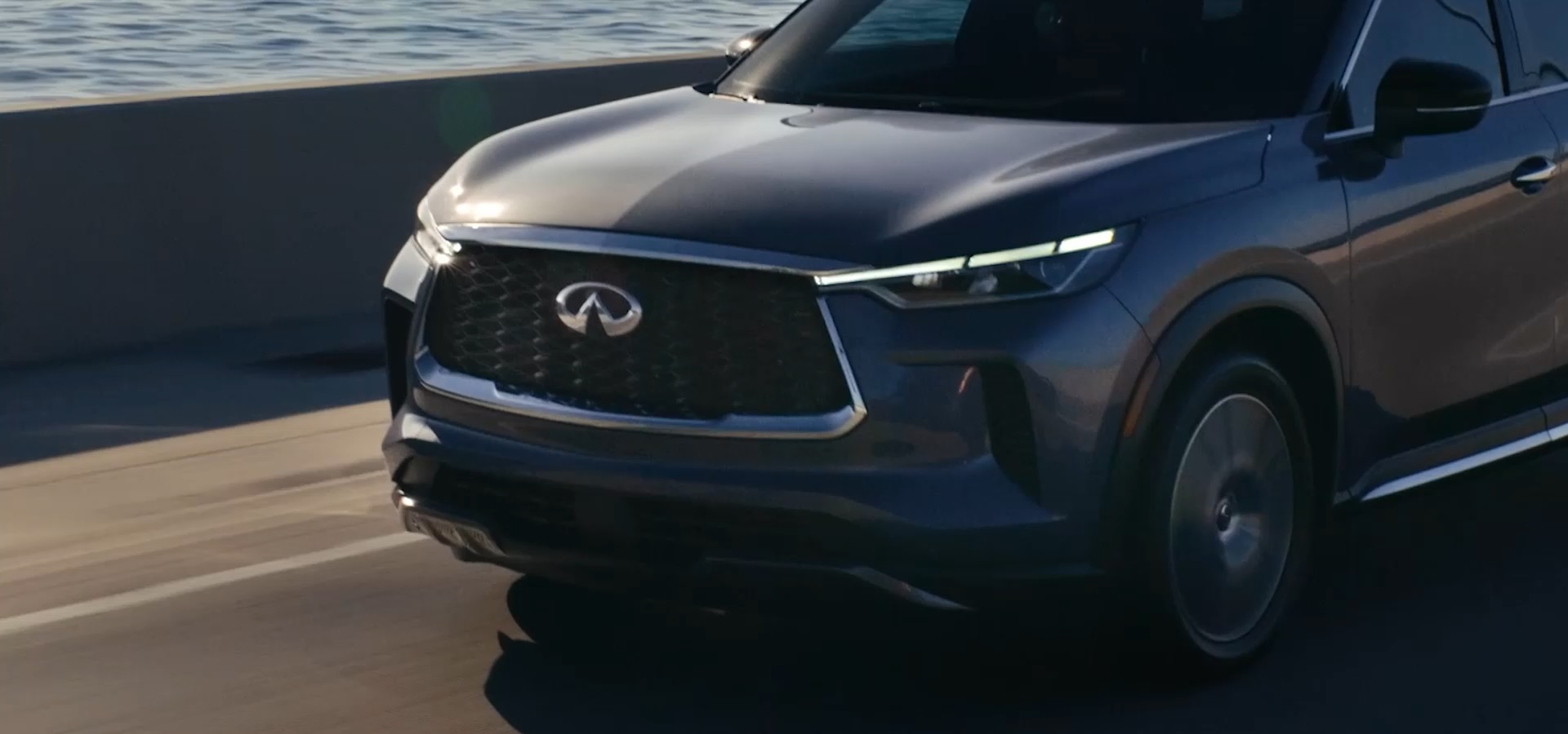 Closeup of 2025 INFINITI QX60 driving on bridge over water